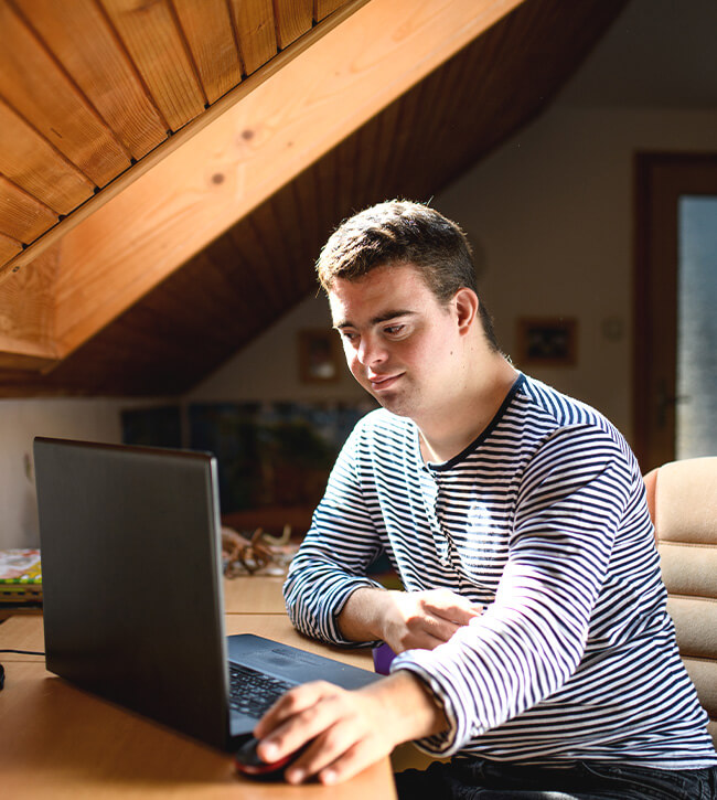 Young Adult Man Sitting On a Chair Using Laptop At Home
